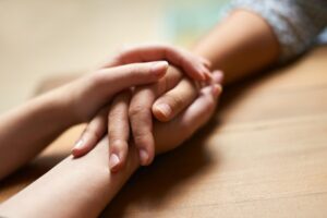 Zwei H&auml;nde umfassen liebevoll und unterst&uuml;tzend eine andere Hand.