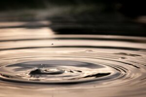 Auf einer ruhigen Wasseroberfl&auml;che zieht sich ein Wasserring langsam nach au&szlig;en.