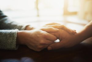 Zwei H&auml;nde umfassen mitf&uuml;hlend eine andere Hand.